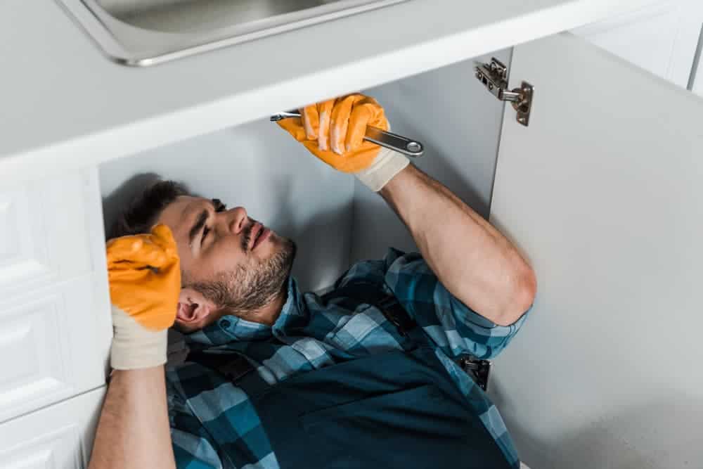 emergency plumber working in kitchen